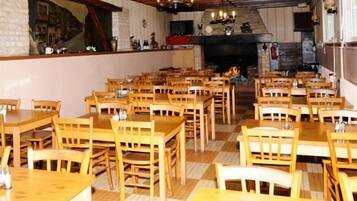 Un restaurante con mesas y sillas de madera, una pared de ladrillo con un mural, y una chimenea.