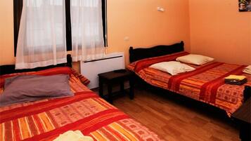 Una habitación con dos camas, una mesita, un calentador y una lámpara colgante.