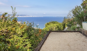 A gravel path leading to a view of the ocean with a sailboat in the distance.