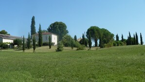 Un champ herbeux avec un bâtiment et des arbres.