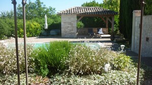 Un jardin avec une piscine, une pergola et un bâtiment en pierre.