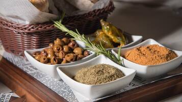 A tray with bread, olives, rosemary, and spices.
