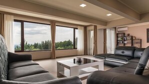 Una sala de estar moderna con un ventanal grande, un sofá de cuero negro, una mesa de centro blanca y una estantería.