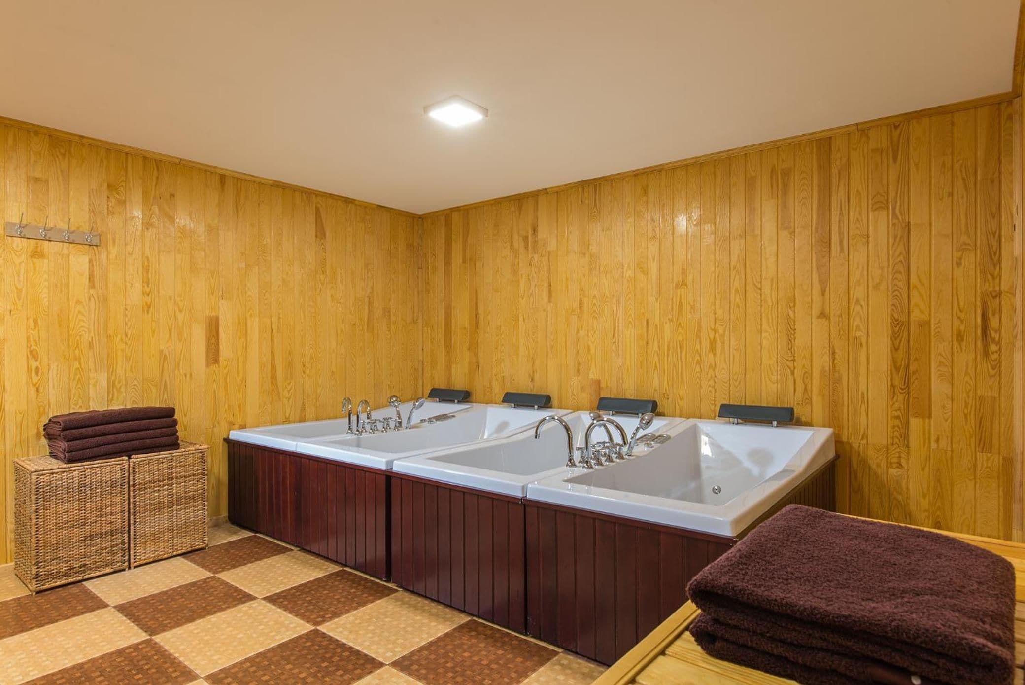 A bathroom with wooden panel walls, a large bathtub, and a checkered floor.
