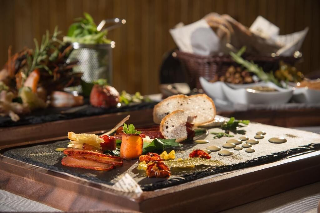 A charcuterie board with various meats, cheeses, and garnishes.