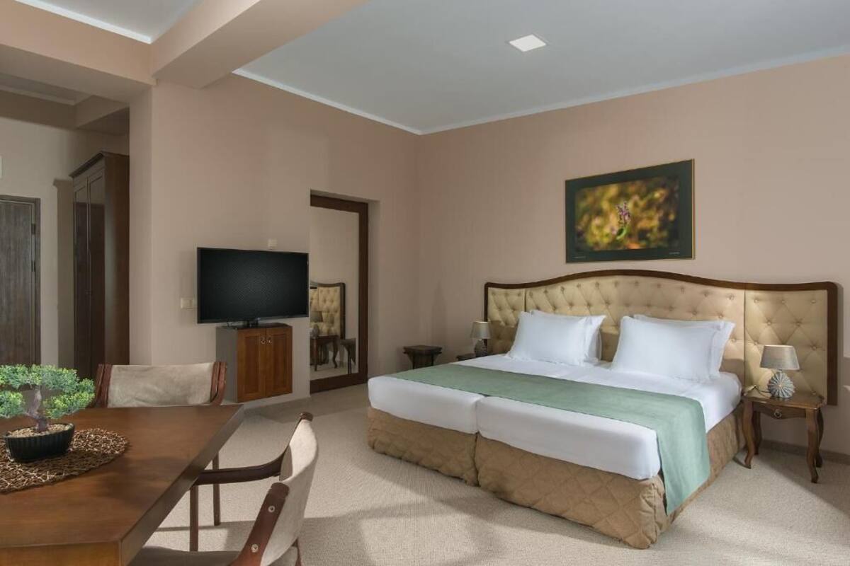 Una habitación de hotel con una cama grande, televisión, una mesa de comedor y una silla.