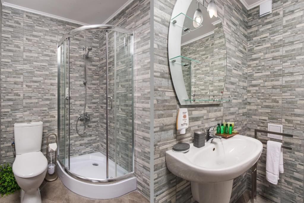 Un baño moderno con ducha de vidrio, inodoro blanco y lavabo con artículos de aseo.