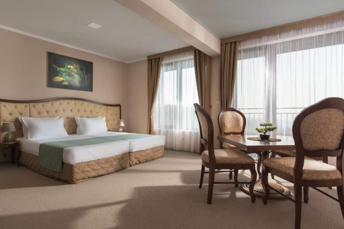 Una habitación de hotel con una cama grande, una mesa de comedor con sillas y un cuadro en la pared.