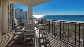 A balcony with a table and chairs, overlooking a beach and a high-rise building. - Two bedroom PREMIUM Gulf Front Condo at Phoenix VII (Orange Beach)