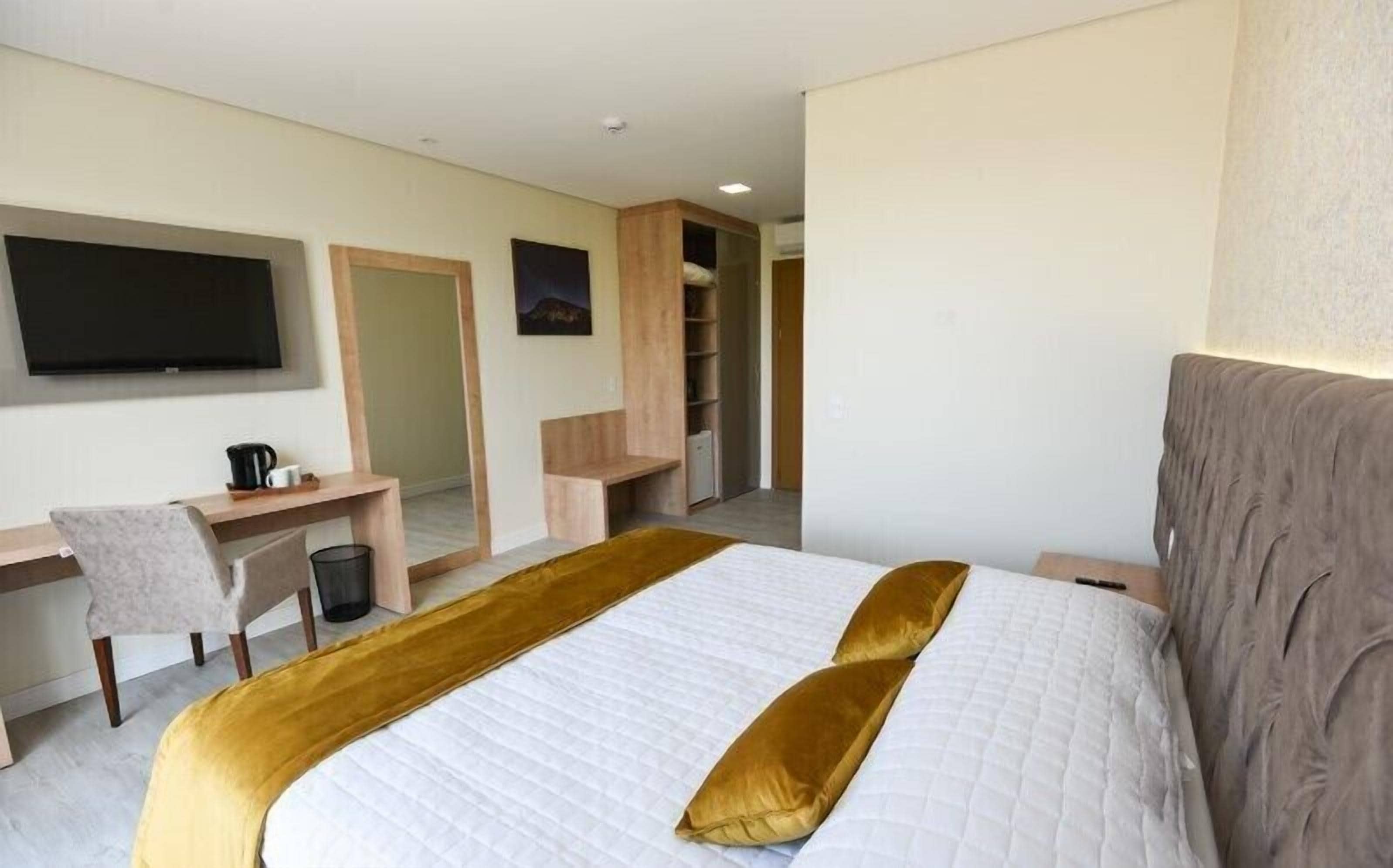 A hotel room with a bed, a desk, a chair, a television, and a wardrobe.