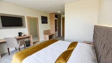 A hotel room with a bed, a desk, a chair, a television, and a wardrobe.