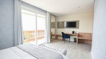 Une chambre d’hôtel avec un grand lit, un bureau avec une chaise, un téléviseur fixé au mur et un balcon avec une balustrade.