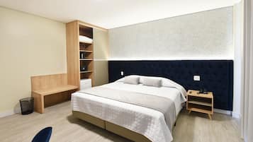 A bedroom with a bed, a wooden bench, a bedside table, and a built-in wardrobe.