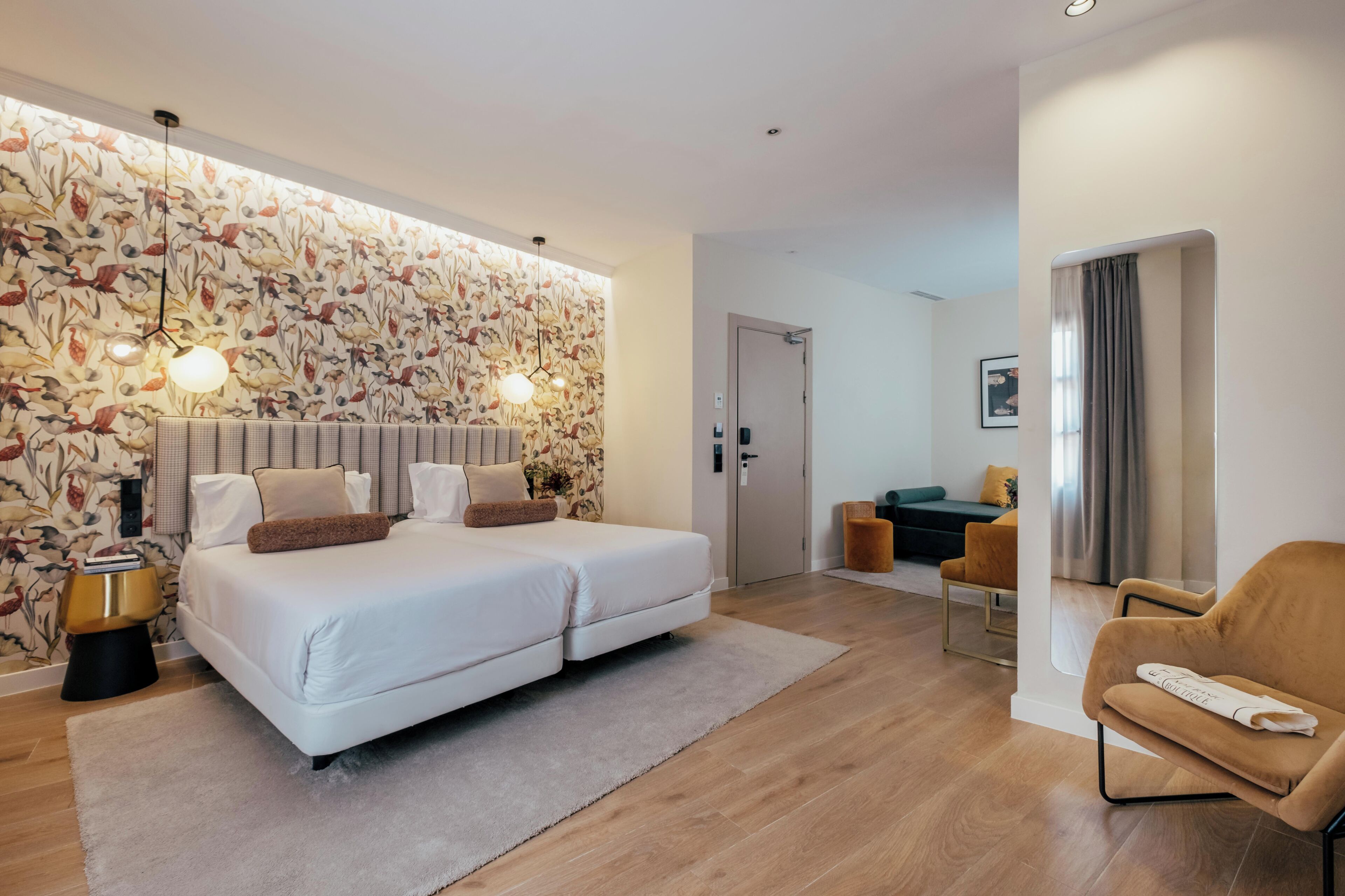 A modern hotel room with a double bed, a desk, a chair, and a decorative wall.