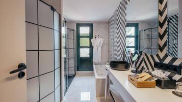 A modern bathroom with a large mirror, a bathtub, and a shower area.