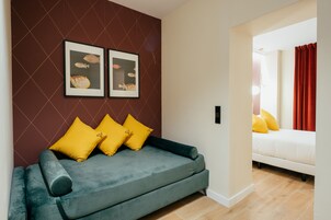 A modern living room with a grey sofa, yellow cushions, and framed fish artwork on the wall.