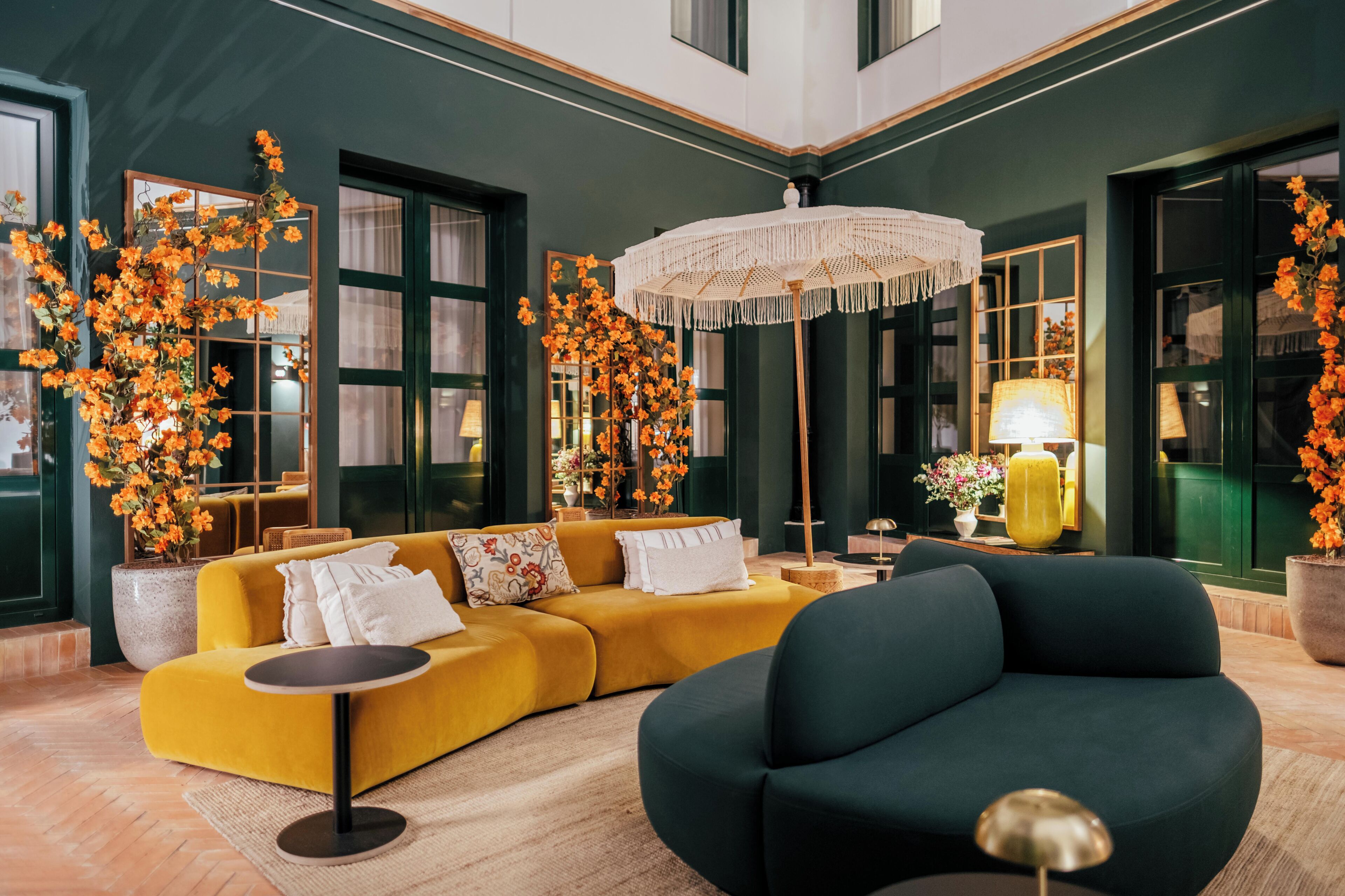 Ein modernes Wohnzimmer mit einem gelben Sofa, einem dunklen Sessel und einer großen Chandelier.