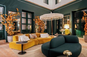 Una sala de estar moderna con un sofá amarillo, un sillón oscuro y una lámpara de araña grande.