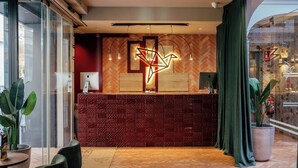 Un área de recepción con una pared de patrón espiga, una instalación de luces moderna y un mostrador con computadoras Apple.