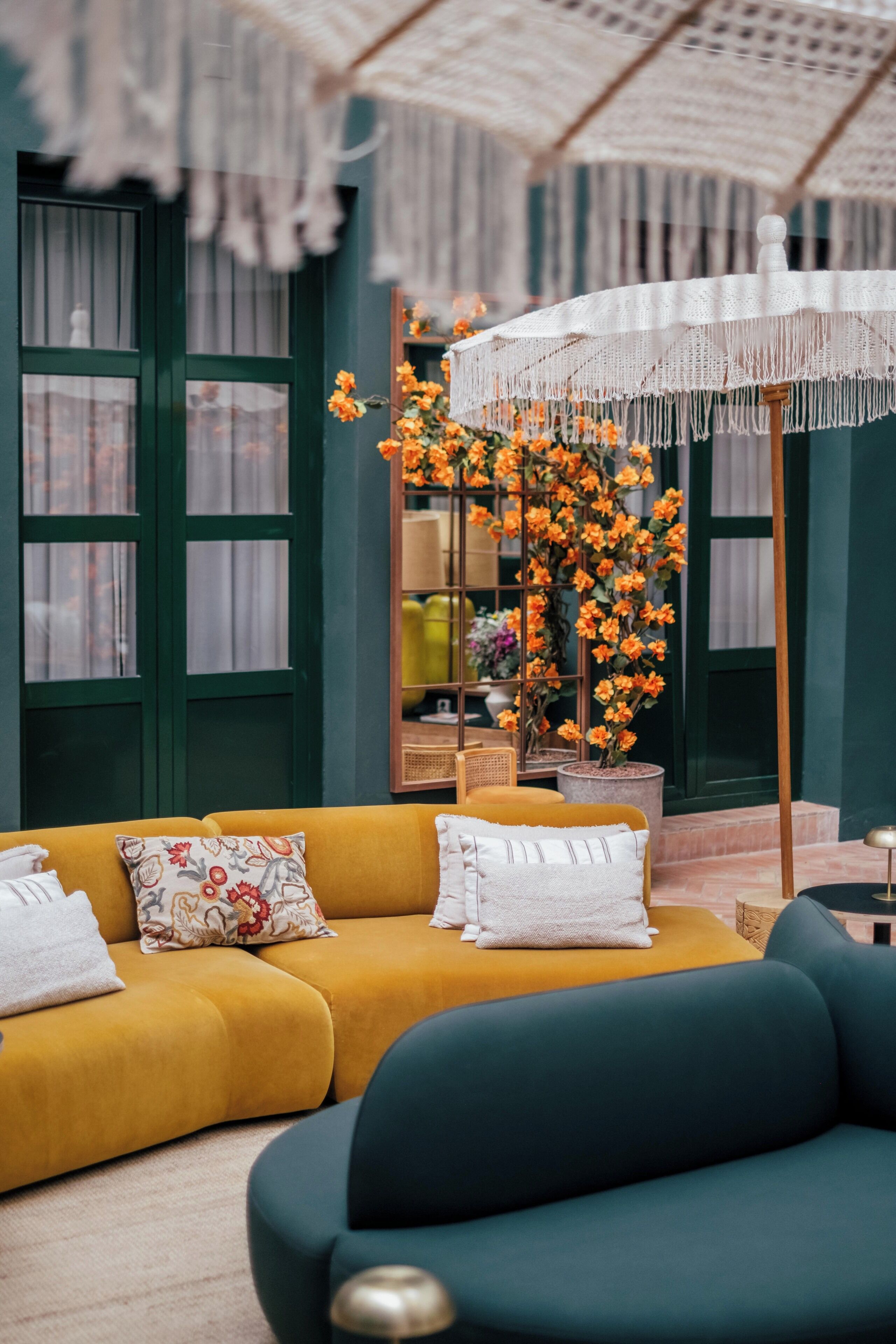 A modern living room with a yellow sofa, a dark blue sofa, and a white macrame umbrella.