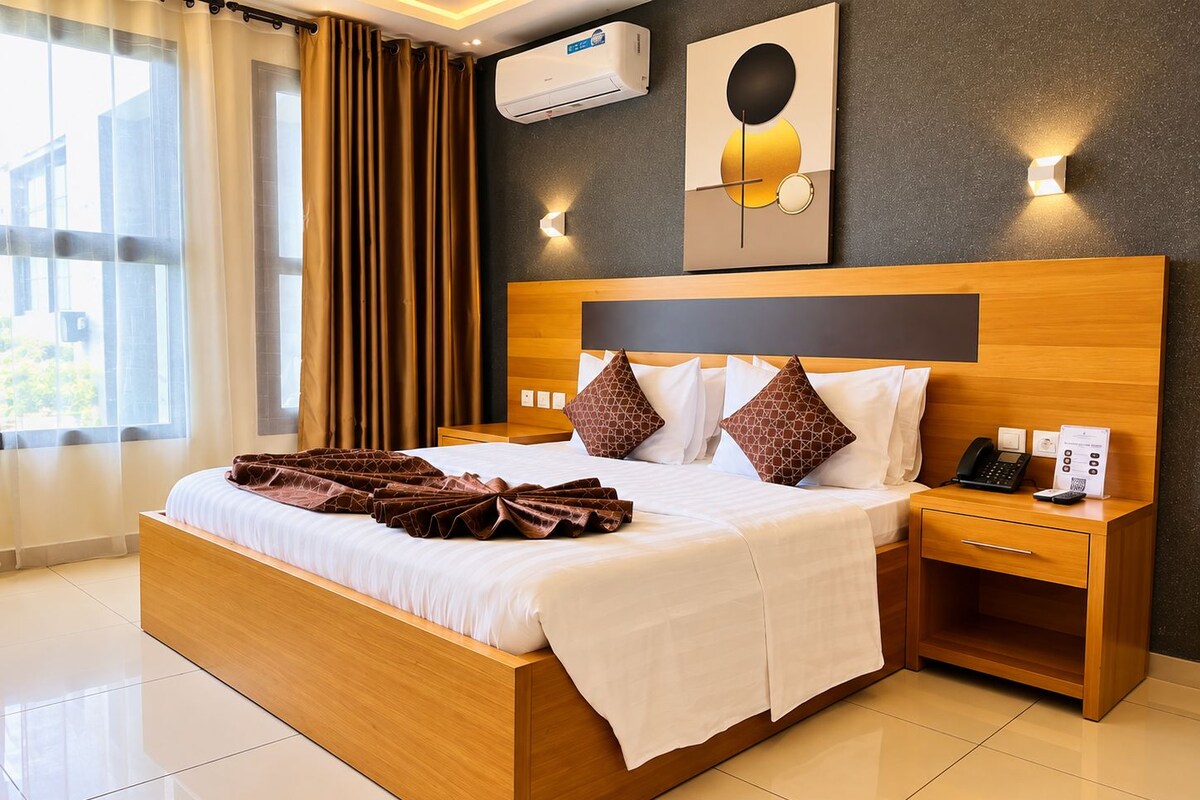 A hotel room with a wooden bed, a nightstand with a phone and a sign, and a wall-mounted air conditioner.