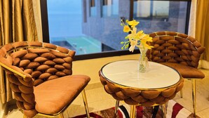 A modern room with two brown upholstered chairs, a small round table, and a vase with yellow flowers. - Atlantic View Hotel (Conakry)