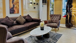 A modern living room with a brown sofa, a round coffee table, and a large painting on the wall. - Atlantic View Hotel (Conakry)