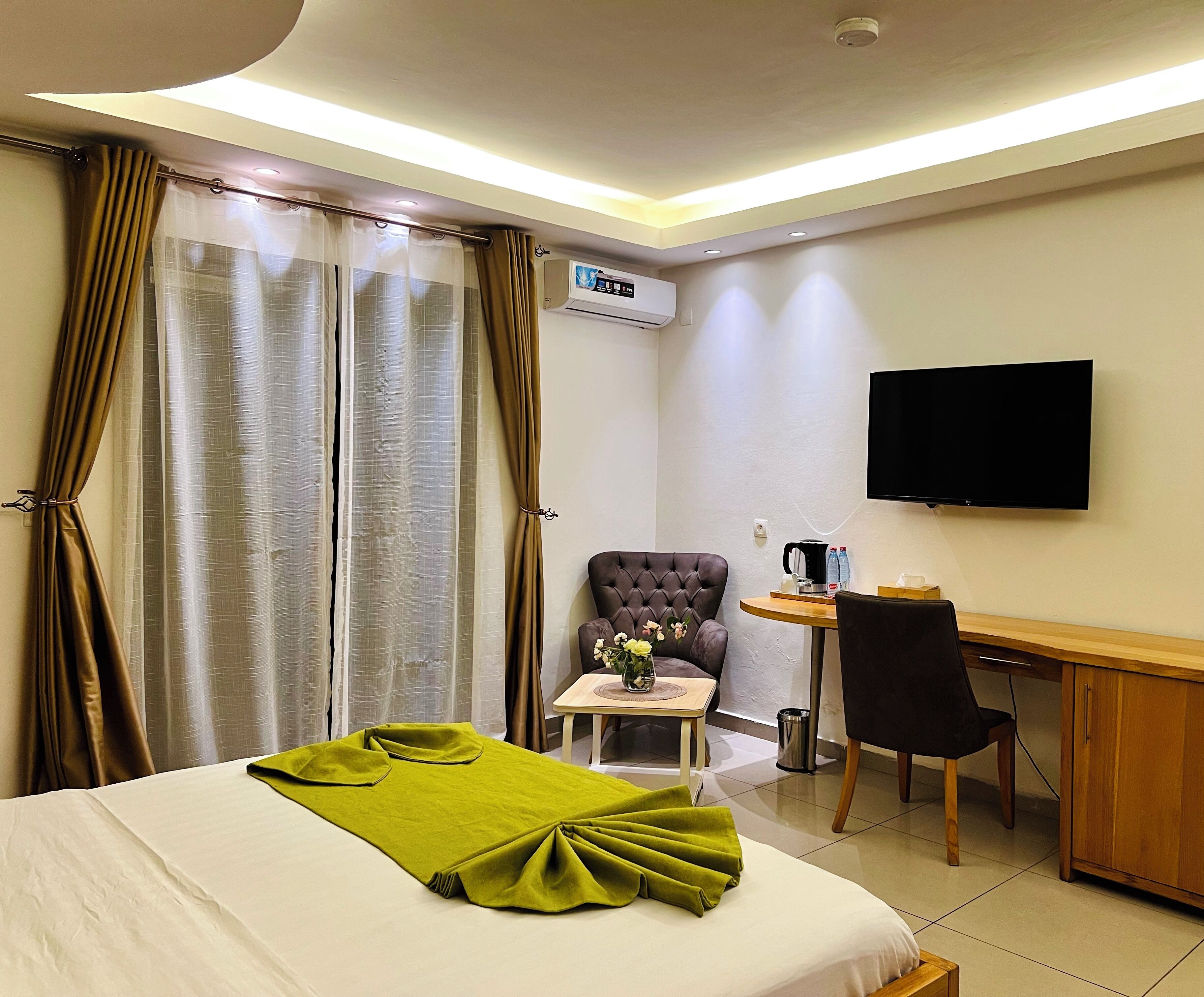 Una habitación de hotel con cama, escritorio, silla, televisión y aire acondicionado.