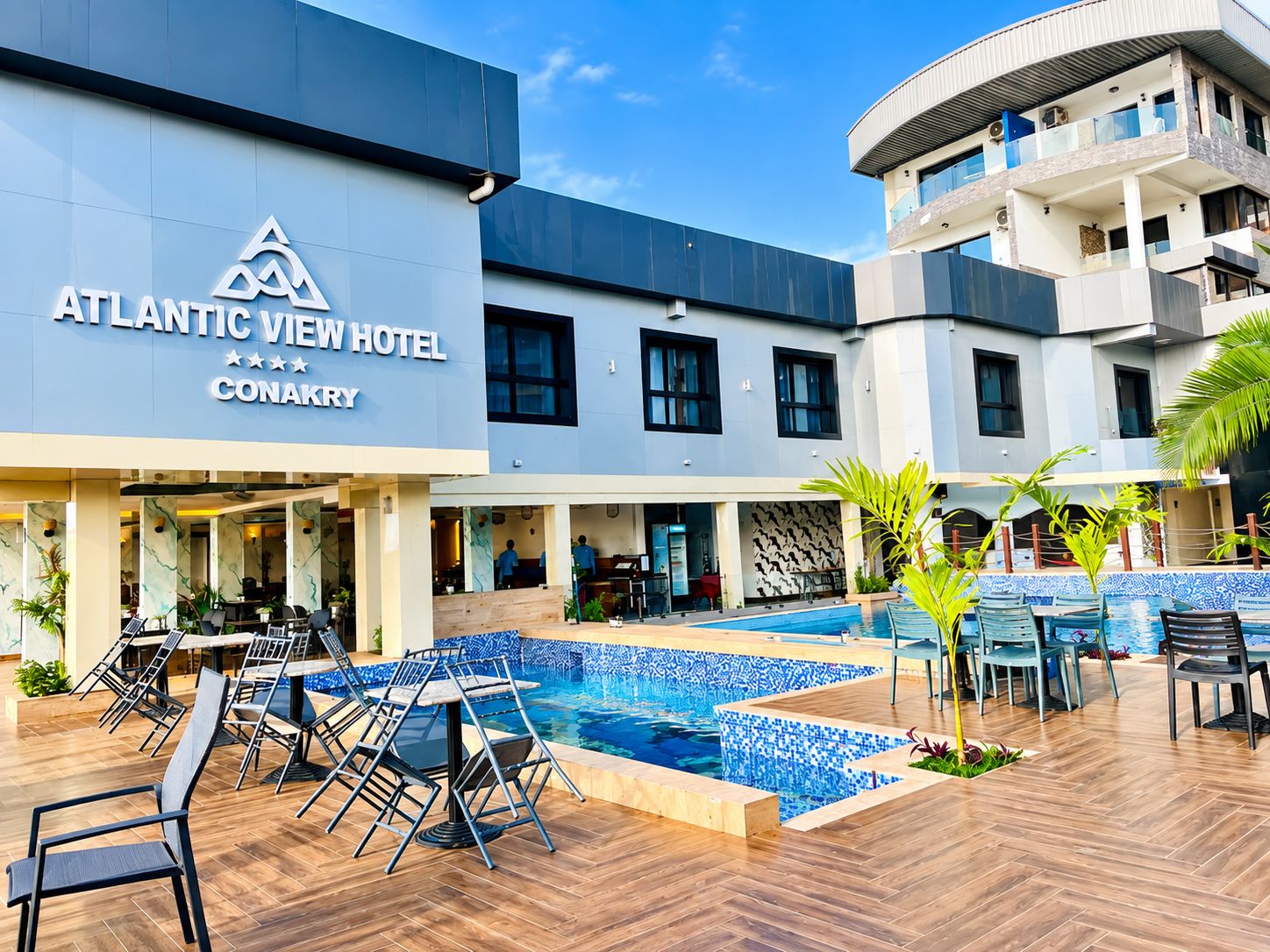 The Atlantic View Hotel Conakry exterior with a swimming pool and outdoor seating area.