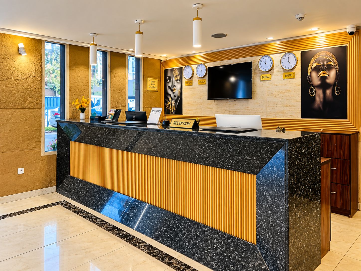 A reception desk with a black marble top, a wooden panel, and a flat-screen TV above it.
