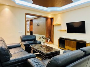 A modern living room with leather sofas, a marble coffee table, a flat-screen TV, and a wooden cabinet. - Atlantic View Hotel (Conakry)