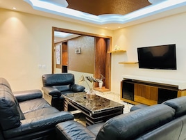 Una sala de estar moderna con sofás de cuero, una mesa de centro de mármol, un televisor de pantalla plana y un mueble de madera.
