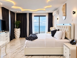 Un dormitorio moderno con una cama grande, una mesita de noche, un televisor y vistas al mar.