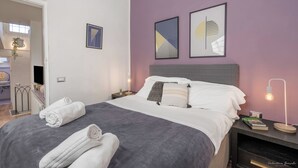 A neatly made bed with rolled towels, a bedside lamp, and two framed artworks on the wall. - Elevator, Ac, Wifi - Heart of historic city center (Florence)