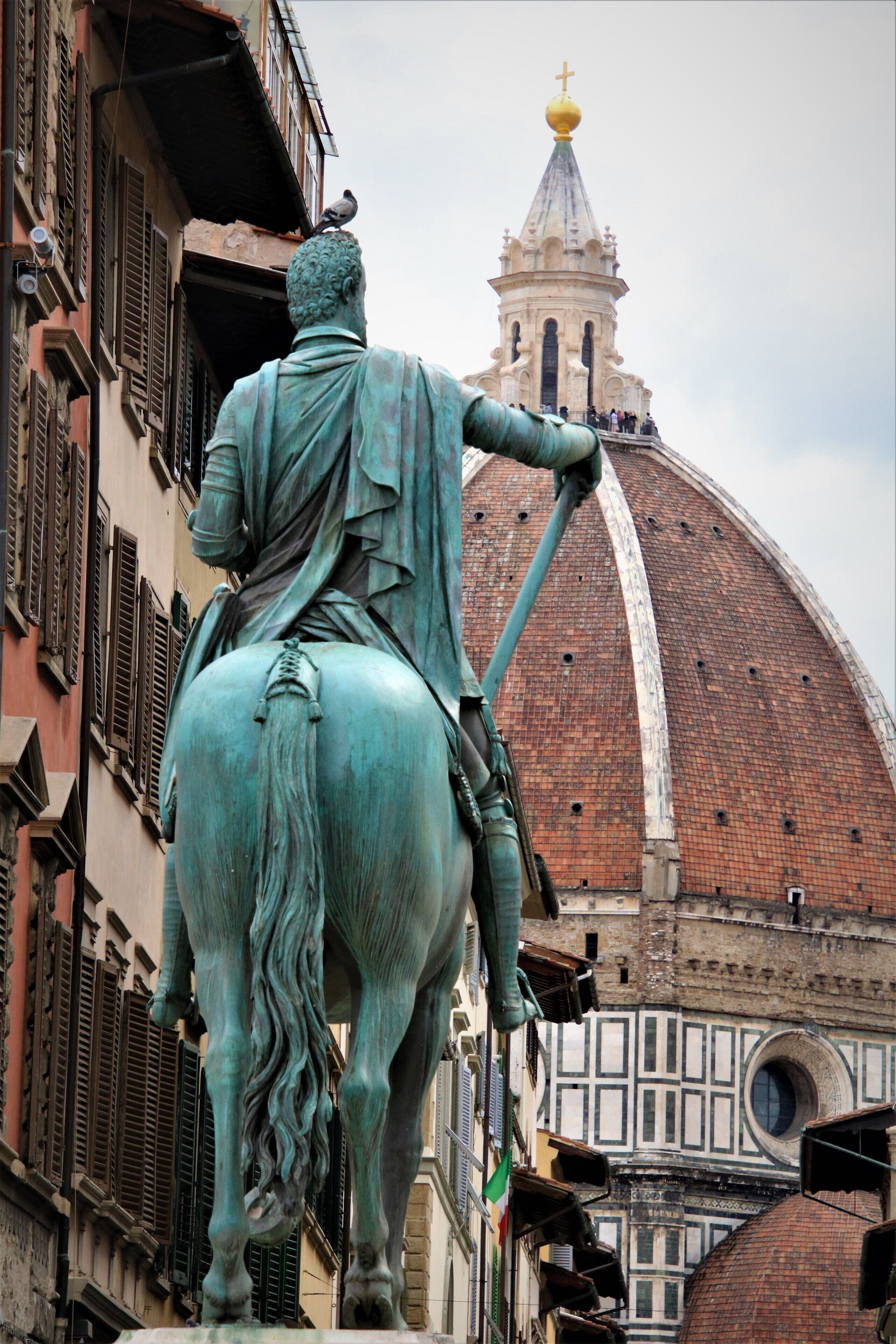 Una estatua de una figura a caballo, con un edificio en el fondo.