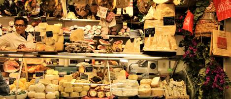 A cheese shop with various cheeses on display and a person behind the counter.
