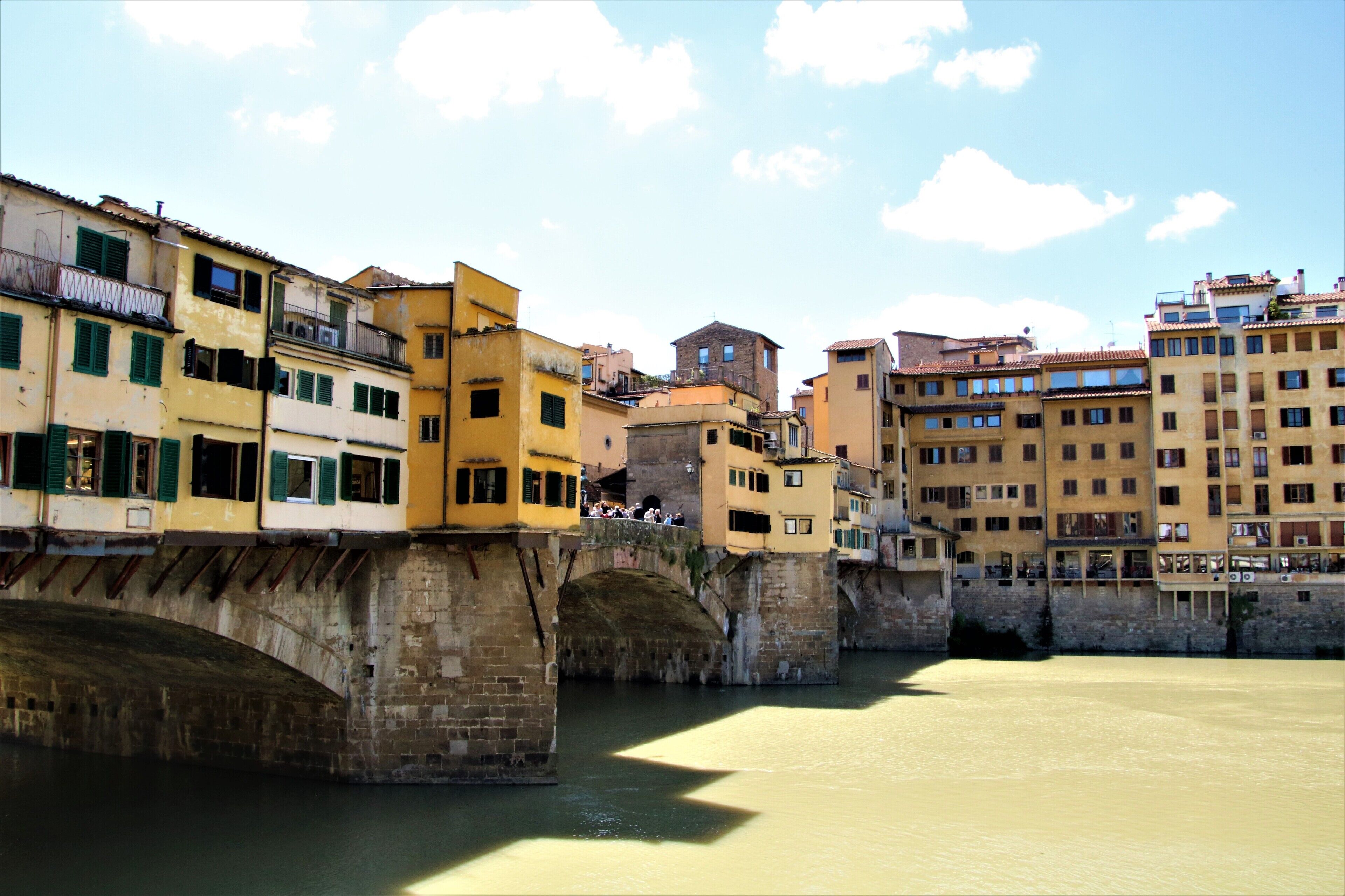Uma ponte de pedra histórica sobre um rio, com edifícios em ambas as margens.