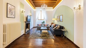 A living room with a fireplace, sofas, a coffee table, and a chandelier. - A Florence Palace - 4 Bedroom Apt - Santa Croce (Florence)