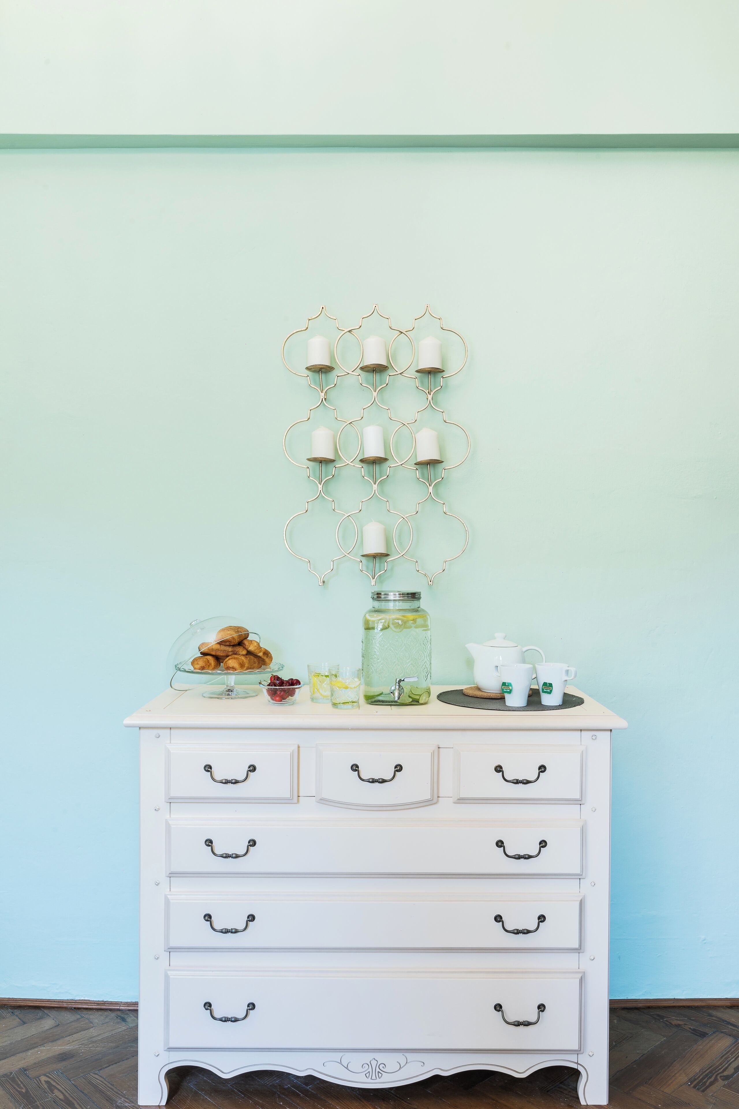 A white dresser with drawers and a glass display case containing pastries.