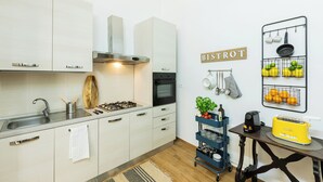 A modern kitchen with white cabinets, a gas stove, a sink, and a wall-mounted rack with kitchen utensils. - A Florence Palace - 4 Bedroom Apt - Santa Croce (Florence)