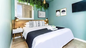 A modern bedroom with a bed, bedside tables, a wall-mounted TV, and a ceiling light fixture. - Trendy Balcony Apartments, Ben Yehuda St, Jerusalem (Jerusalem)