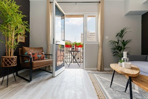 Un salon moderne avec un canapé, une table basse en bois et une porte-fenêtre coulissante donnant sur une terrasse extérieure.