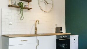 A modern kitchen with white cabinetry, a wooden countertop, a built-in oven, and a wall-mounted clock. - New - Trendy One Bedroom Apt, Most Popular Area (Jerusalem)