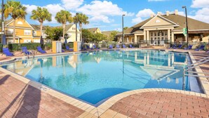 A swimming pool with lounge chairs and palm trees, surrounded by buildings with a brick pathway. - 4 Bedroom Townhouse, Resort, 15 Mins to Disney, Themed Rooms perfect for Kids (Kissimmee)