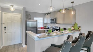 Una cocina moderna con una isla central, electrodomésticos de acero inoxidable e iluminación colgante.
