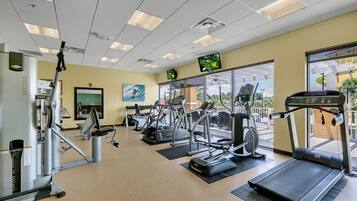 Une salle de sport équipée de tapis de course, de vélos elliptiques et d'appareils de musculation.