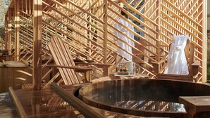 Une terrasse en bois avec un jacuzzi, des chaises en bois et un porte-serviettes.