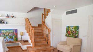 A staircase with wooden railings, a beige armchair, and a colorful painting on the wall. - Villa 100 meters from the sea, in the Platja de Pals Golf Club. A/C (Pals)