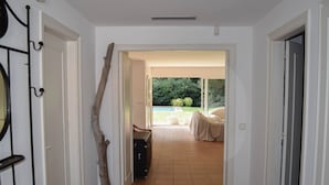A hallway with a wooden sculpture, a suitcase, and a view of a garden and outdoor seating area. - Villa 100 meters from the sea, in the Platja de Pals Golf Club. A/C (Pals)