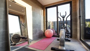 Un gimnasio moderno con equipo de ejercicio, un espejo grande y una colchoneta rosa.